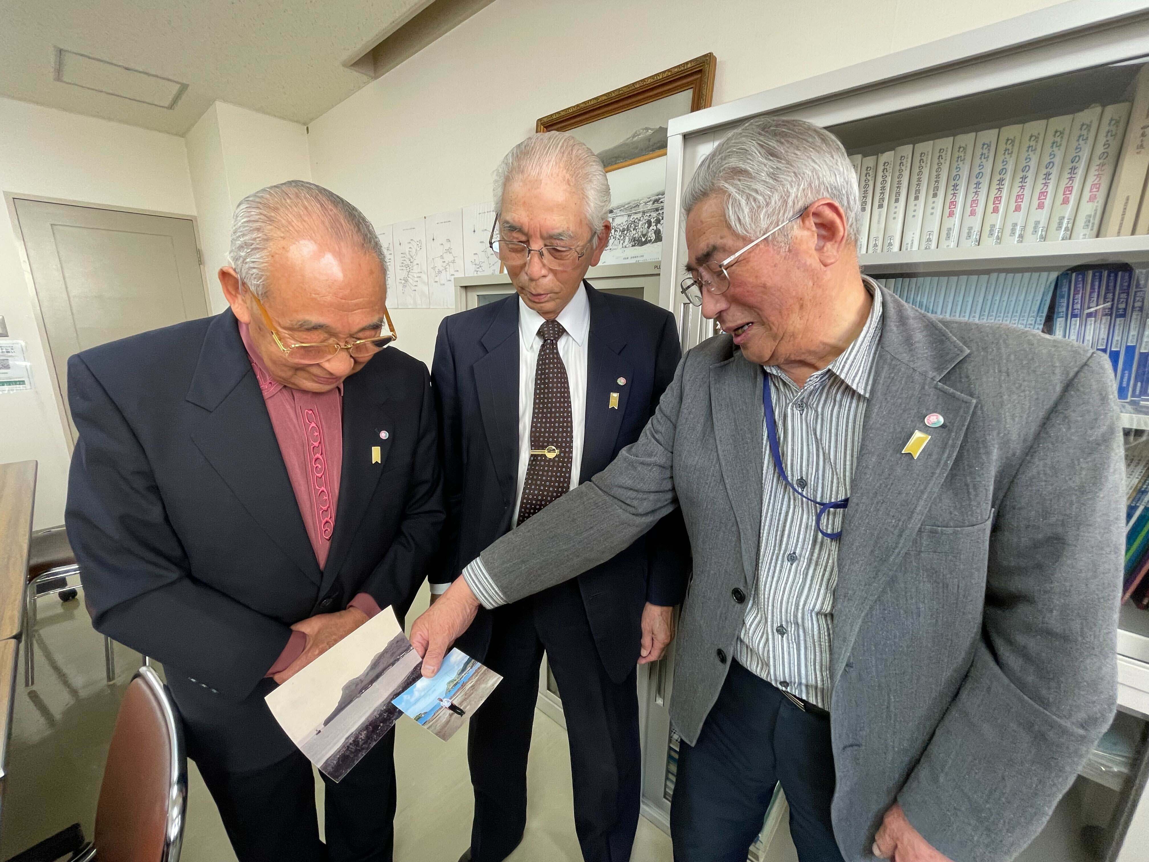 <p>Yasuji Tsunoka, Hirotoshi Kawata and Hiroshi Tokuno, former residents of the Northern Territories, look at photos from their home islands</p>