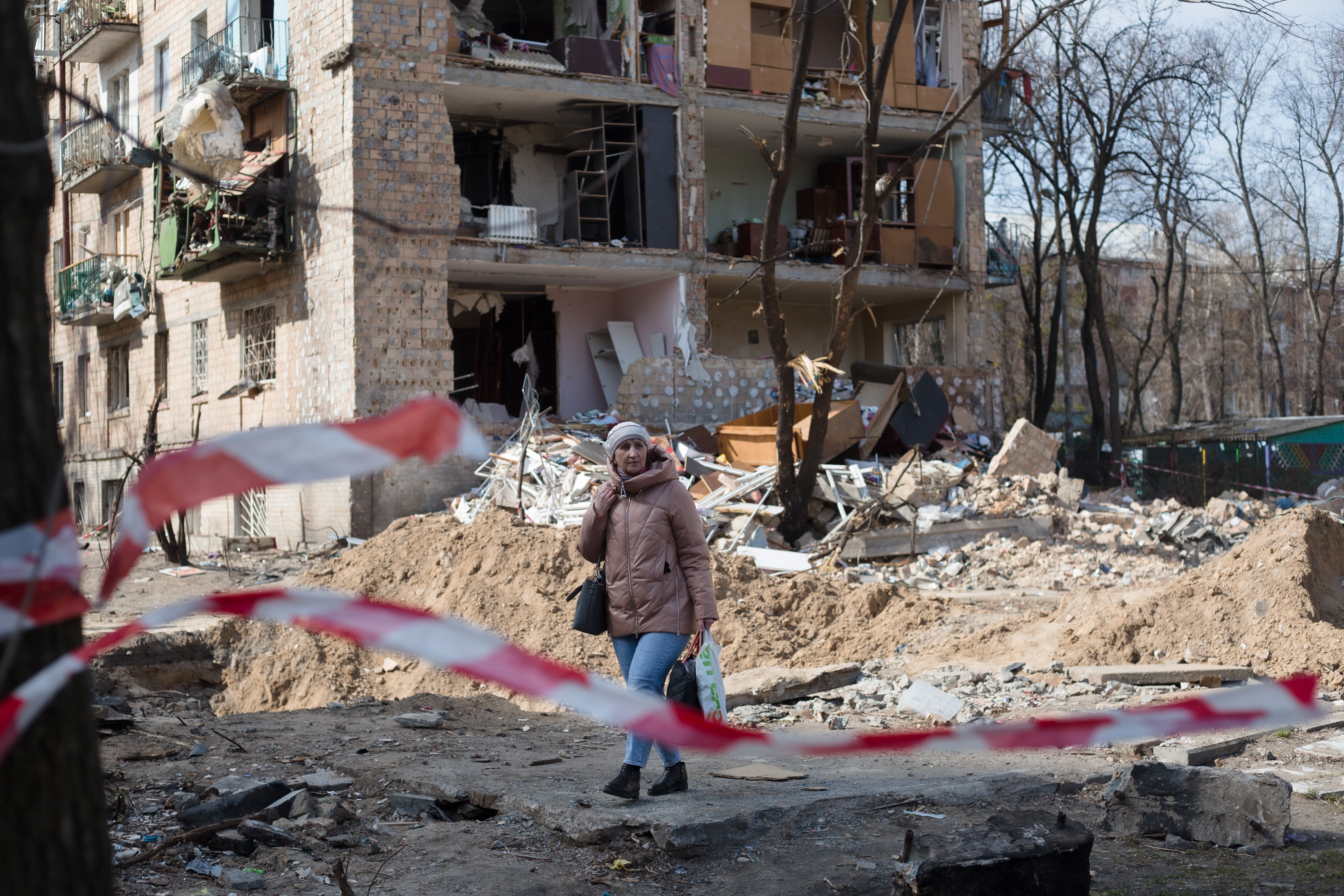 A woman walks past a residential area that was destroyed as a result of a rocket strike two weeks ago on 28 March in Kyiv