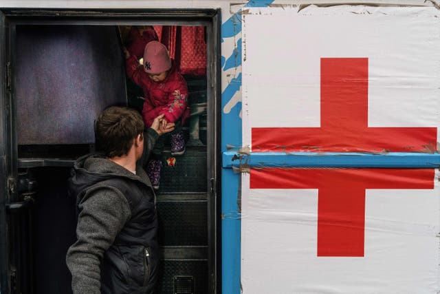 <p>A child is helped off a bus at the registration centre in Zaporizhzhia, where the International Committee of the Red Cross said it had a team of three cars and nine staff waiting to head out towards the besieged city of Mariupol, 1 April 2022</p>