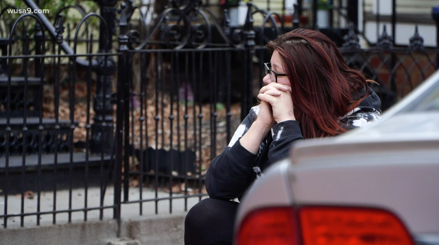 <p>Lauren Handy waits outside as police raid her home in Washington, DC</p>