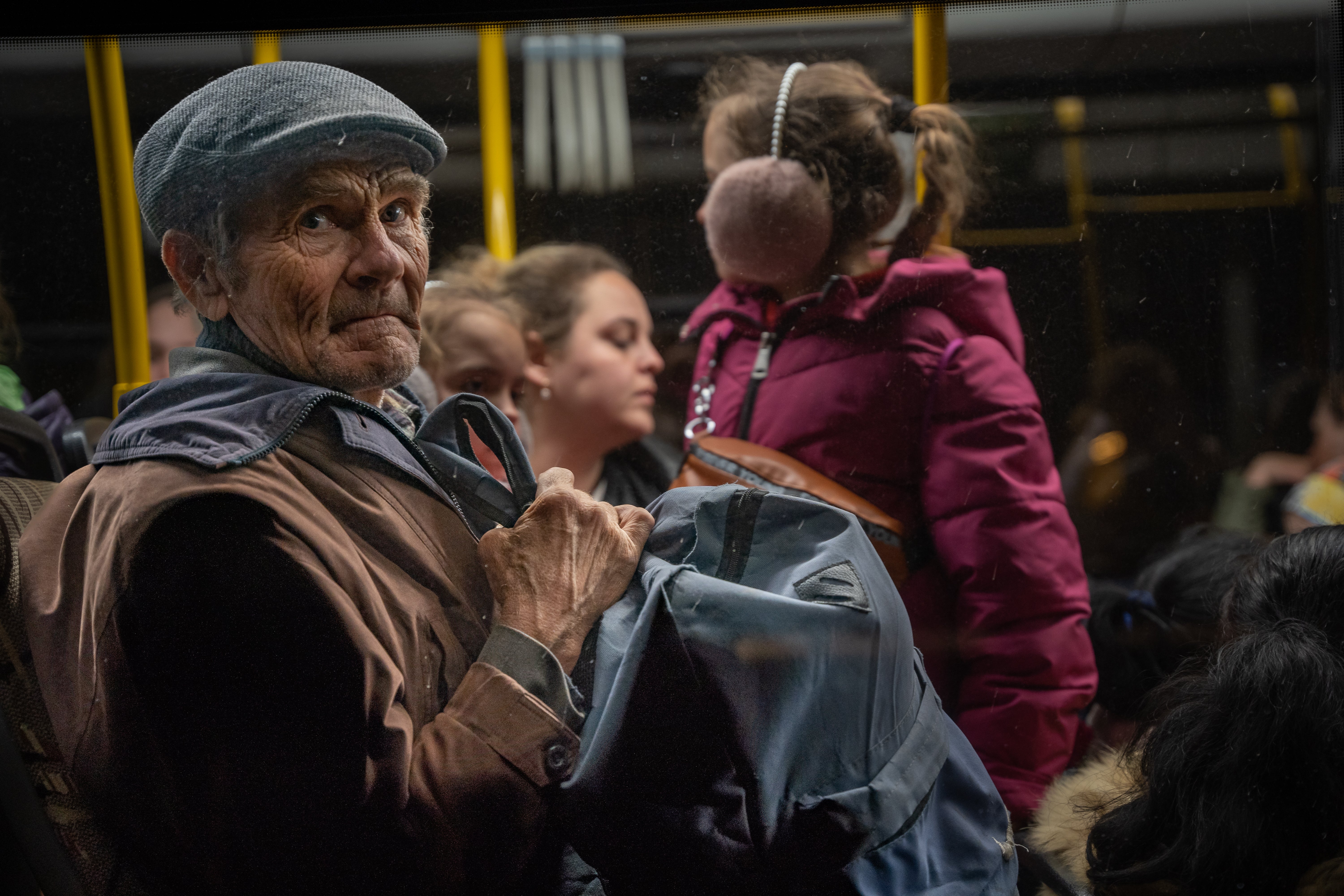 An elderly man looks out the window of an evacuation bus after fleeing Mariupol