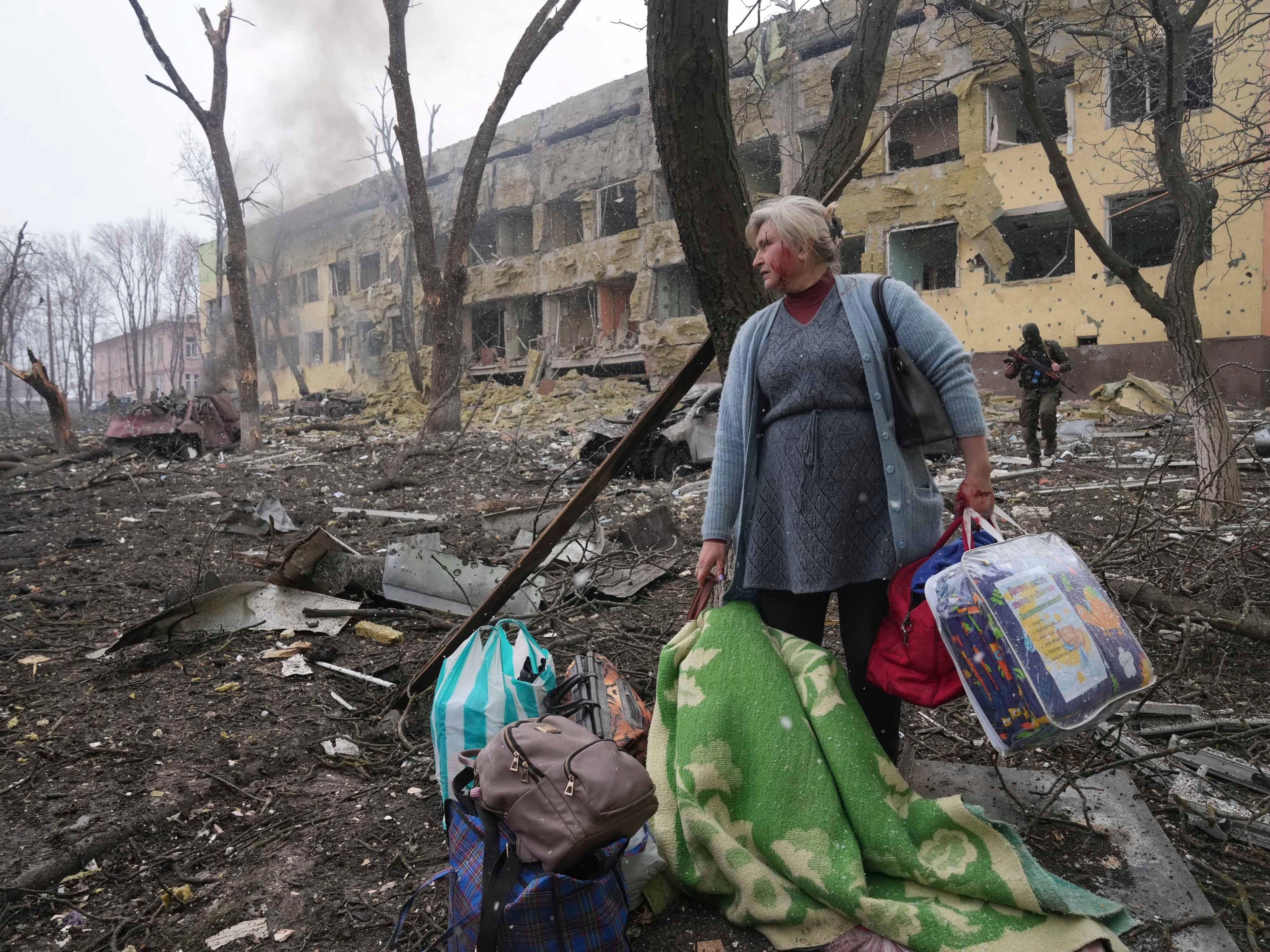 A woman walks outside a maternity hospital damaged by shelling in Mariupol