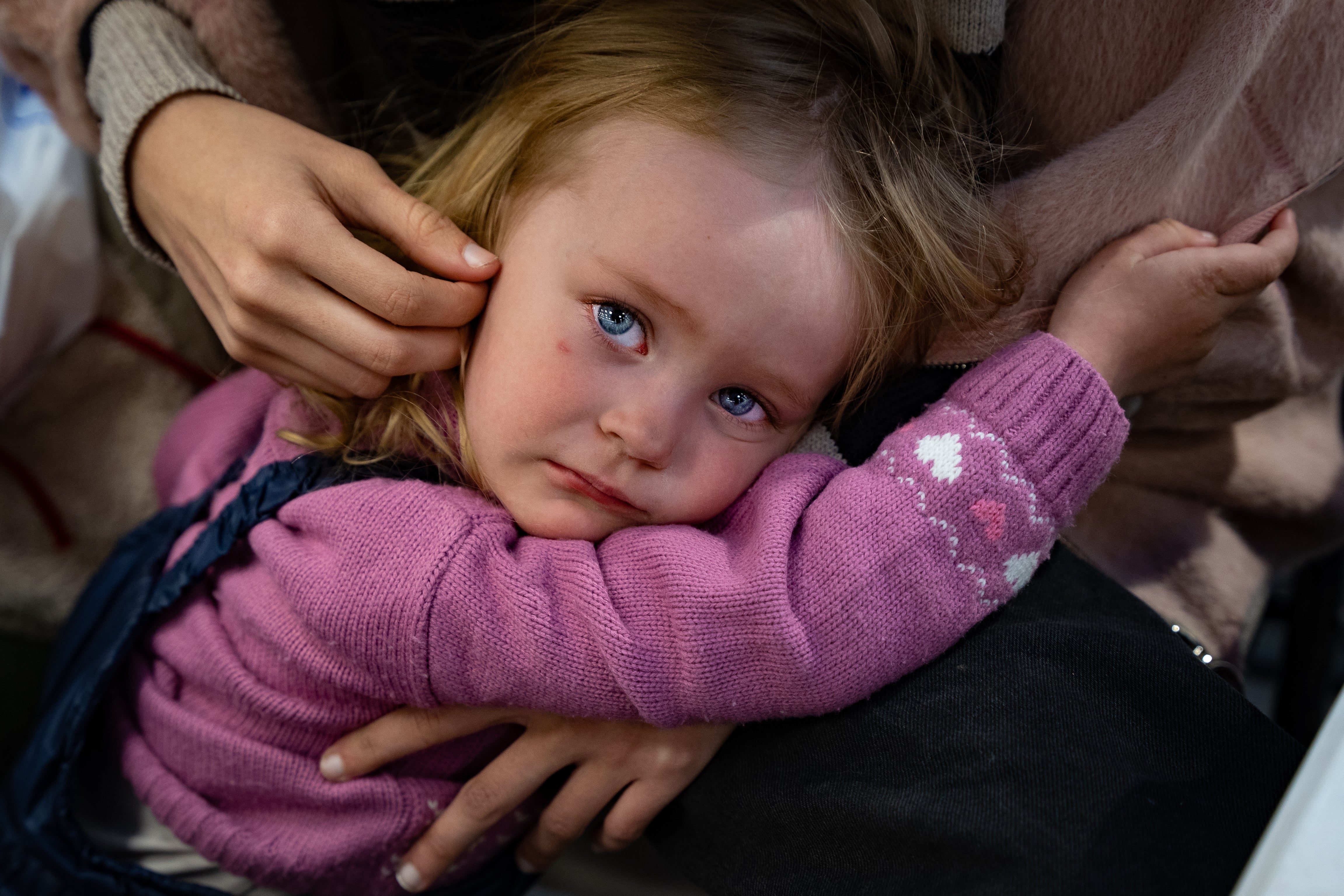 Paulina, 2, is comforted by her sister after fleeing intense shelling in Mariupol