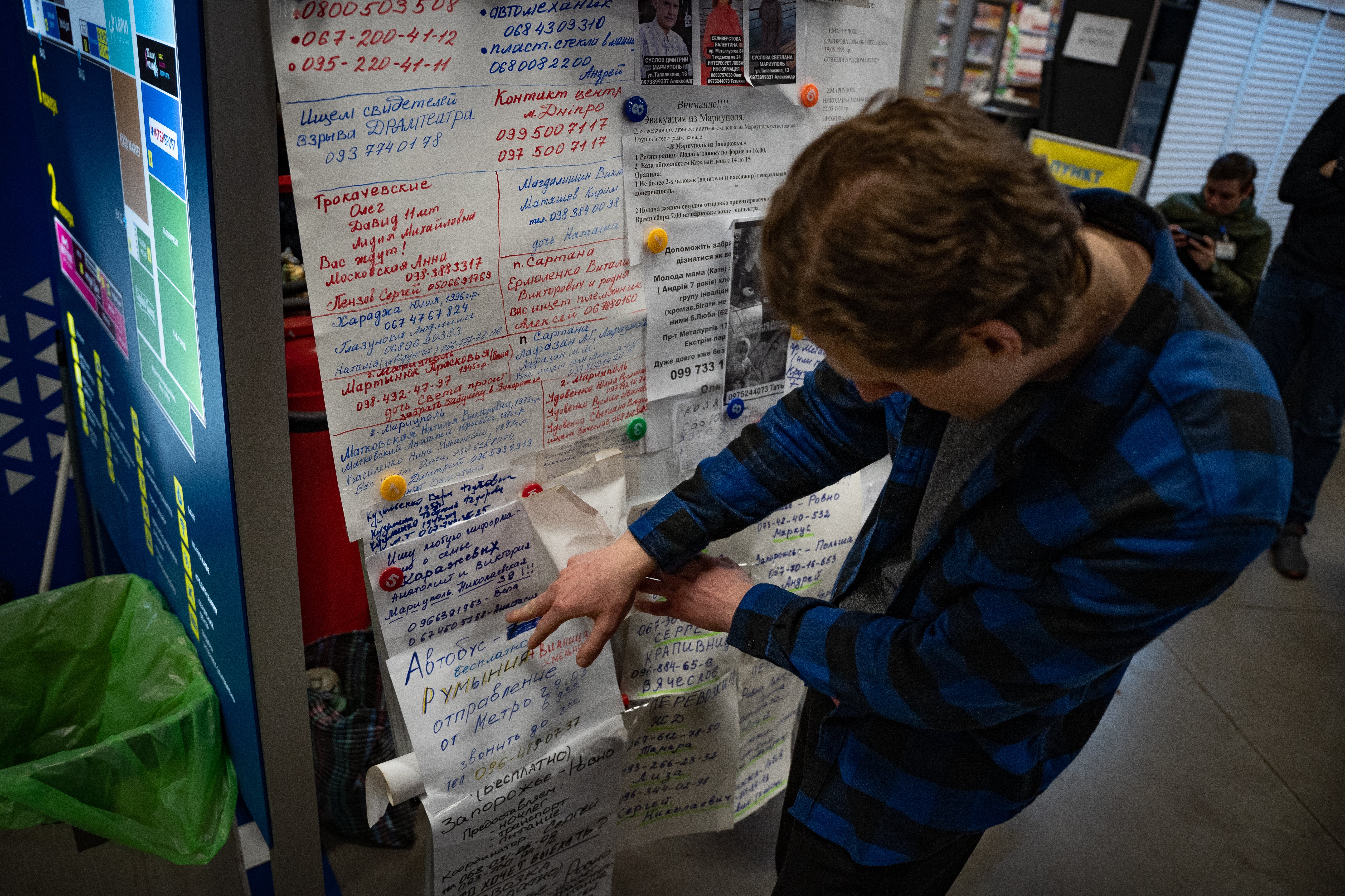 A volunteer goes through the messages families have posted about their missing relatives in Mariupol