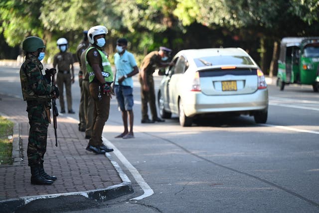 <p>Army soldiers stand guard at a checkpoint after authorities imposed a weekend nationwide curfew to contain protests over a worsening economic crisis, in Colombo on 3 April</p>