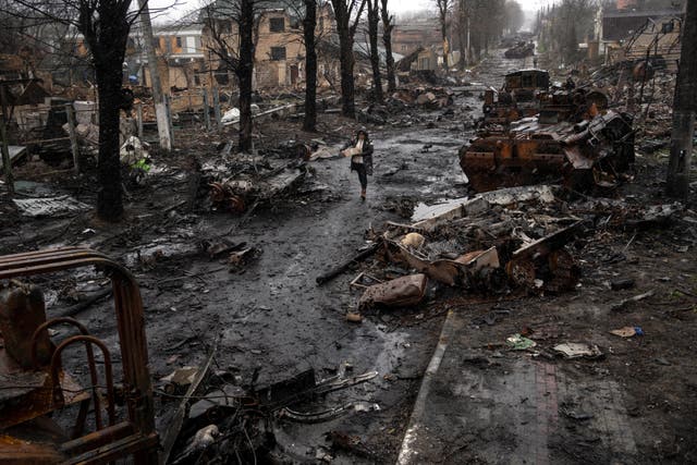 <p>A woman walks among destroyed Russian tanks in Bucha, on the outskirts of Kyiv, Ukraine, 3 April 2022</p>