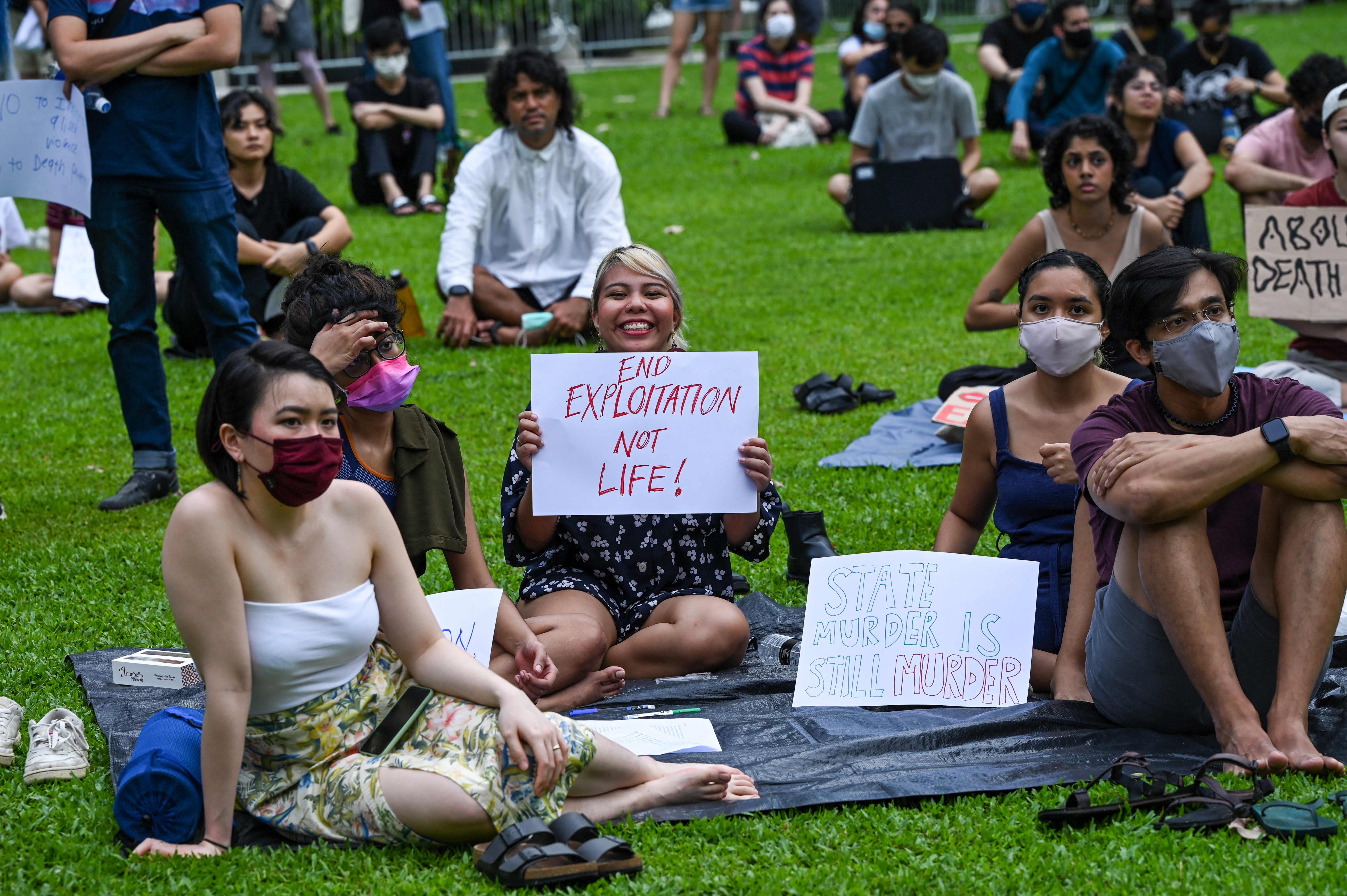 Attendees hold signs during a protest against the death penalty at Speakers' Corner in Singapore on 3 April