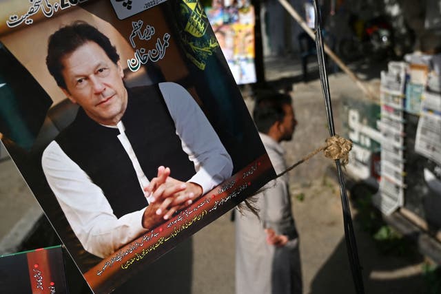 <p>A resident stands beside a picture of Pakistan's Prime Minister Imran Khan as he looks at the morning newspapers displayed for sale at a roadside stall in Islamabad </p>