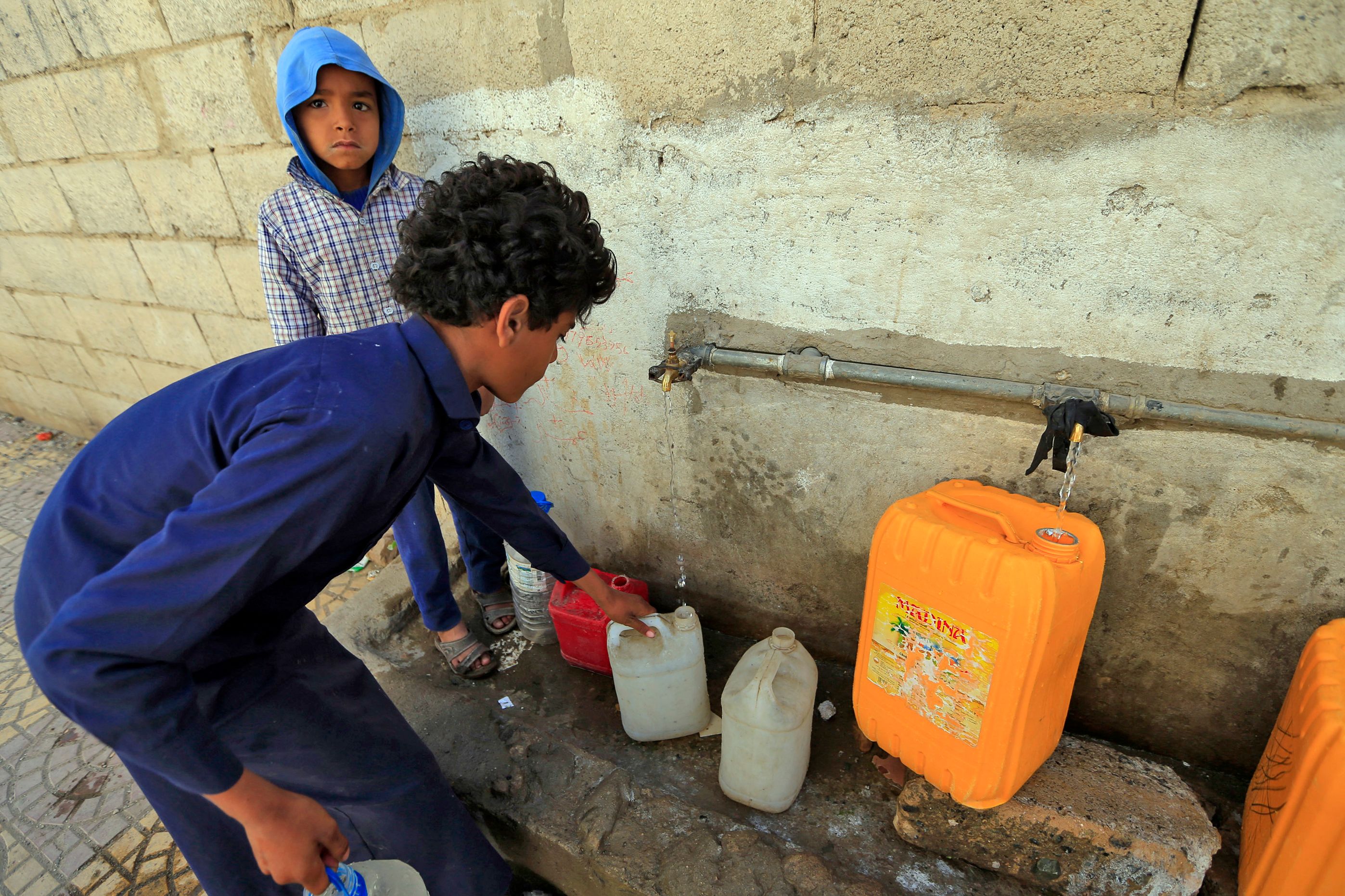 Yemenis fill their jerrycans with drinking water from a donated tank amid acute shortage in the capital