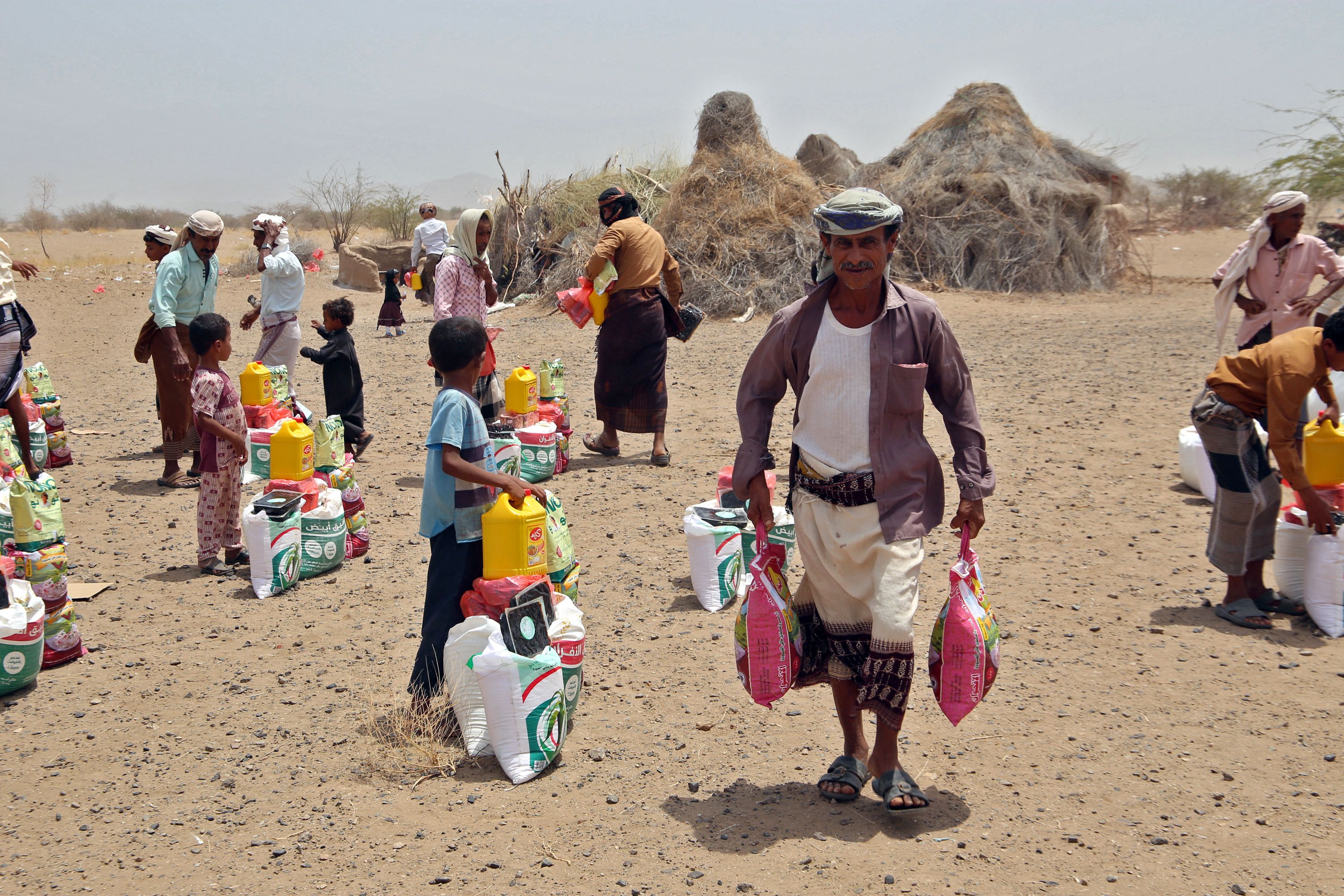 Yemenis displaced by the conflict receive food aid and supplies to meet their basic needs at a camp in Hays district in the war-ravaged western province of Hodeidah