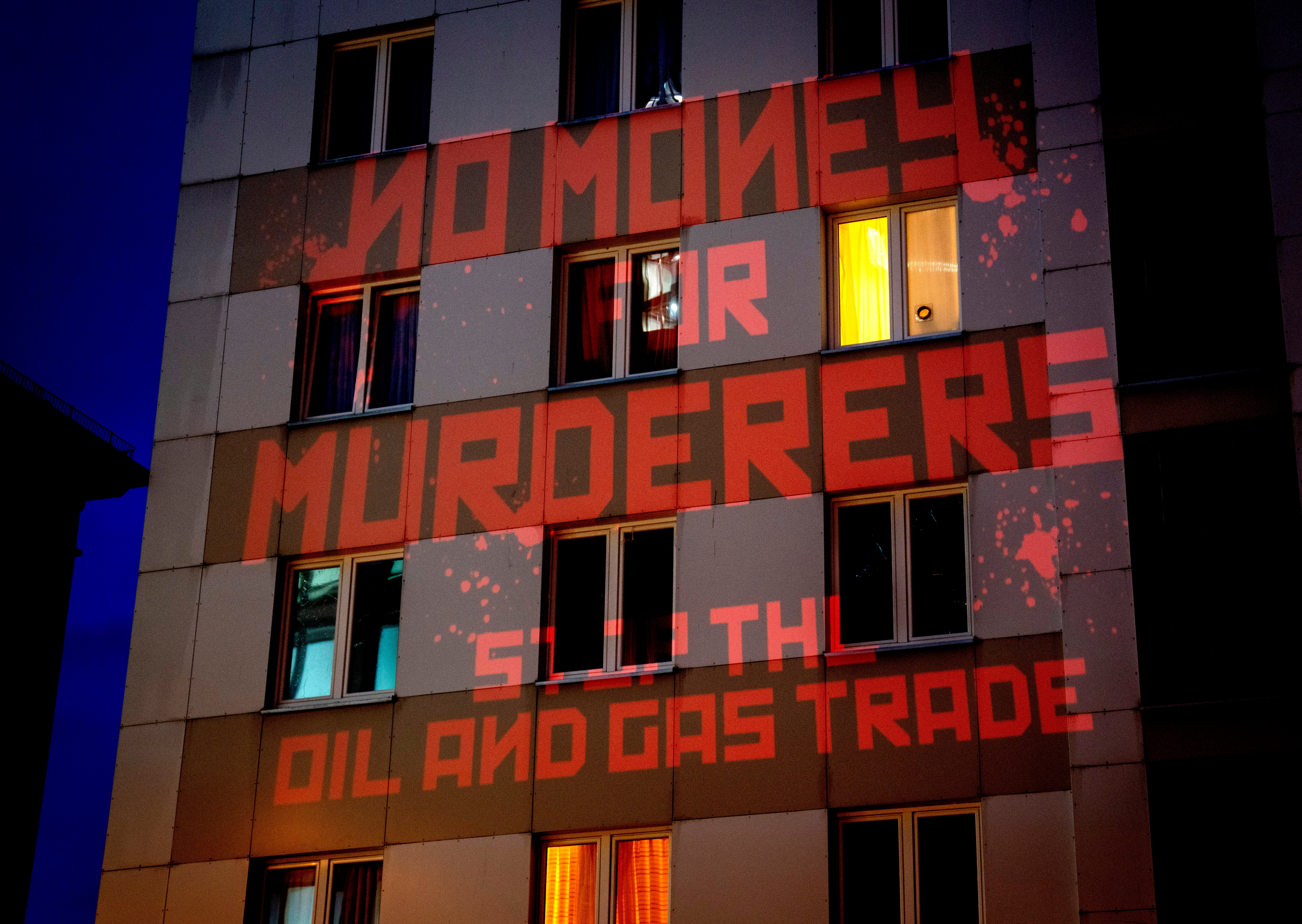 The words ‘No Money for Murderers, Stop the Oil and Gas Trade’ are projected by activists onto the Russian consulate in Frankfurt