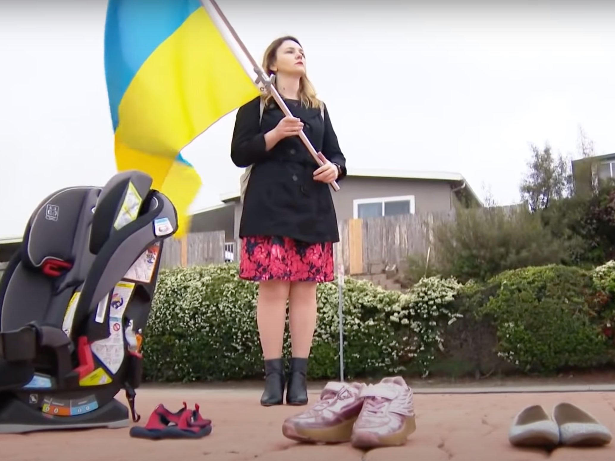 A protester with a Ukrainian flag and shoes repressing those confirmed killed by Russia