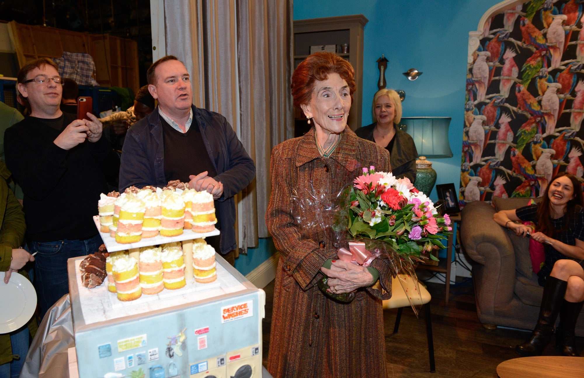 Adam Woodyatt, Sean O’Connor, Sharon Batten and Lacey Turner surprise June Brown with cake and flowers to help her celebrate her 90th birthday on the set of EastEnders (Kieron McCarron/PA)