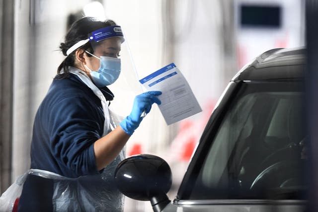 <p>A medical worker talks to a member of the public waiting in their car to take a test for Covid</p>