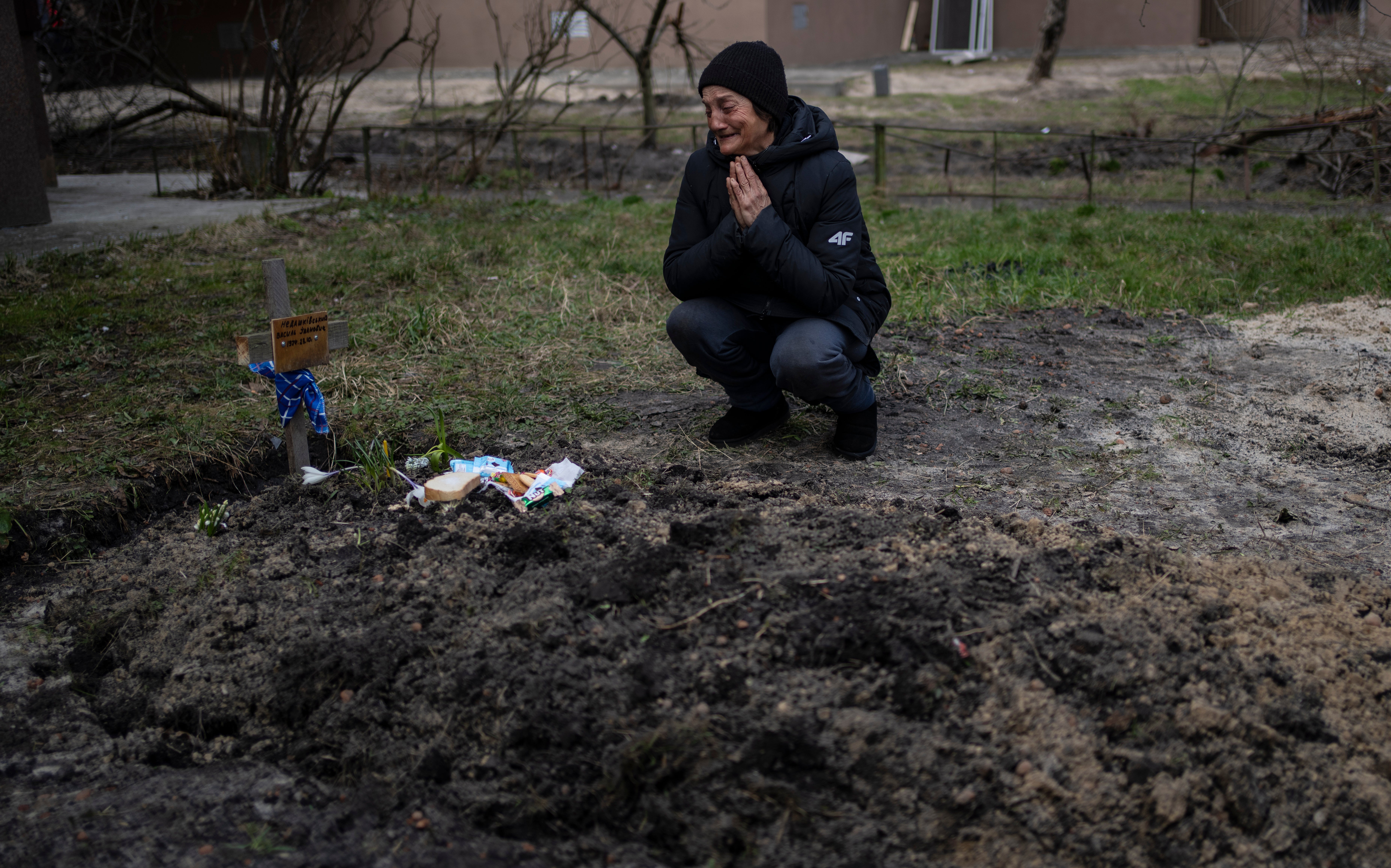 A woman cries by a grave in Bucha (Rodrigo Abd/AP)
