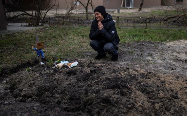 A woman cries by a grave in Bucha (Rodrigo Abd/AP)