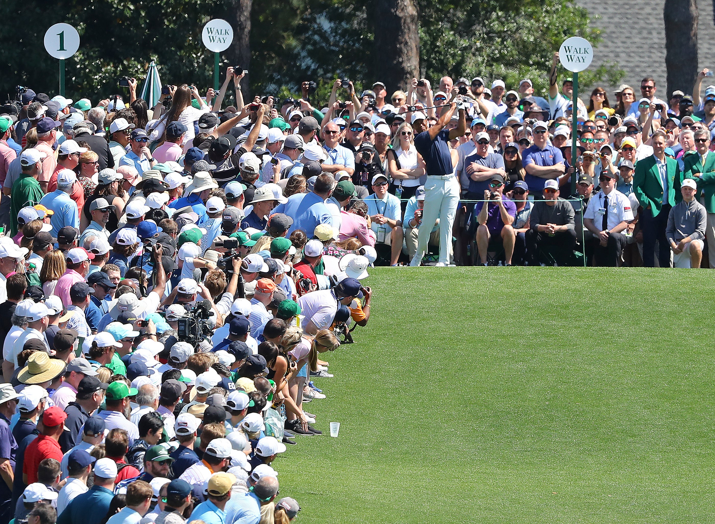 Spectators watch Tiger Woods tee off during a practice round for the 86th Masters (Curtis Compton/Atlanta Journal-Constitution via AP)