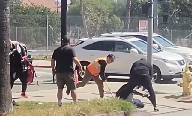 <p>Onlookers surround a man who they allegedly saw abusing a small dog in Hollywood on Monday</p>