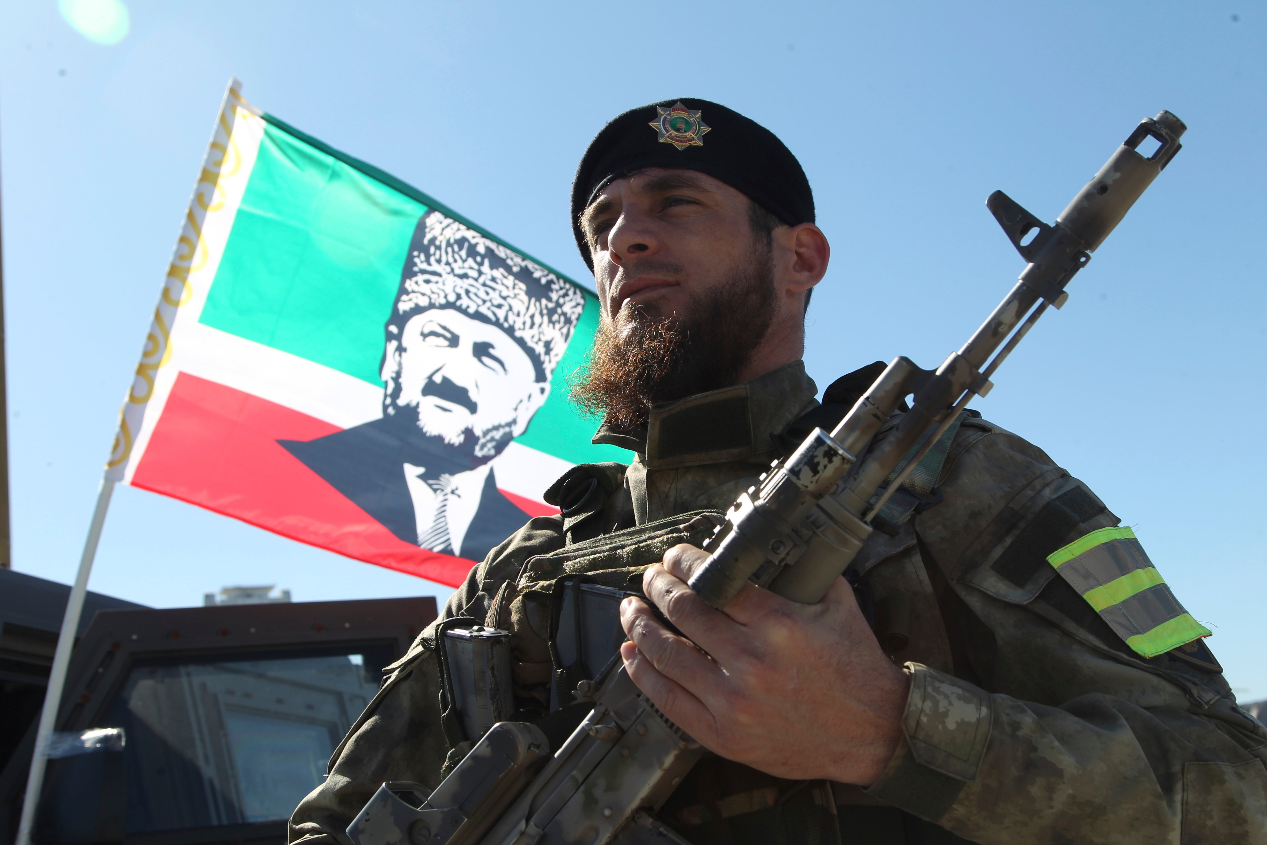 A serviceman stands in front of a flag of Akhmad Kadyrov and listens as Ramzan Kadyrov speaks to troops in Grozny, 29 March 2022