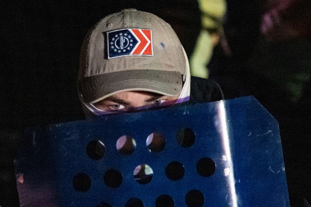 <p>A member of the rightwing group Patriot Front peers over his shield after marching on the National Mall on 4 December 2021 in Arlington, Virginia</p>