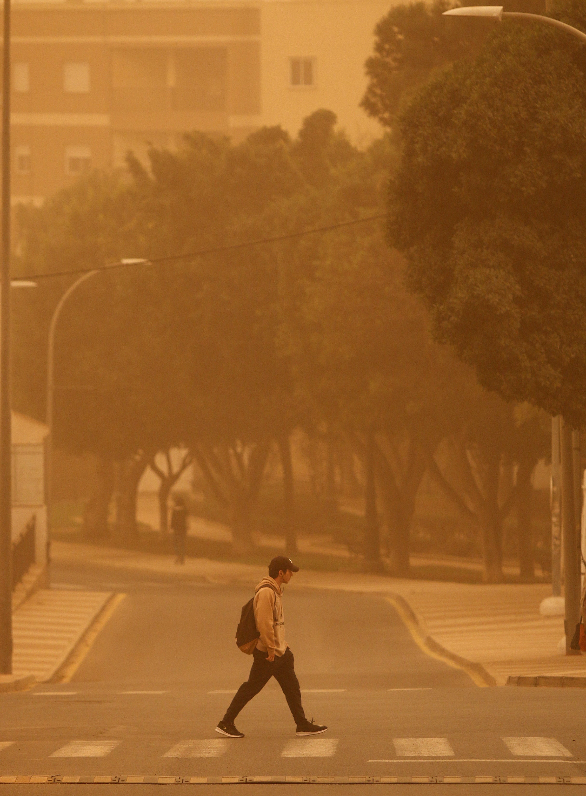 A man crosses a road as dust from the Sahara desert blankets the coastal city of Roquetas de Mar, Spain, 15 March