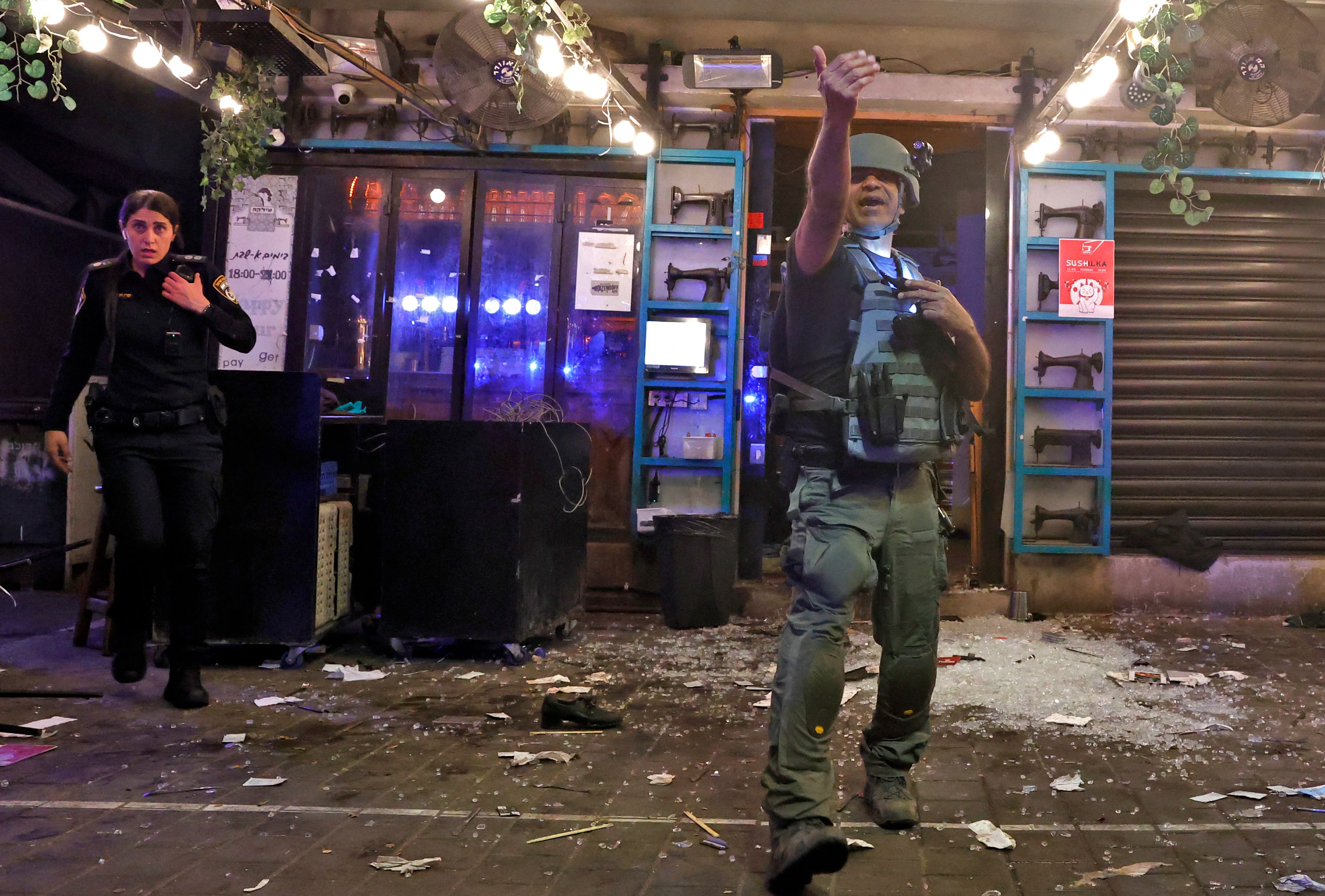 A policeman gestures at the scene in the aftermath of a shooting attack in Dizengoff Street in the centre of Israel's Mediterranean coastal city of Tel Aviv