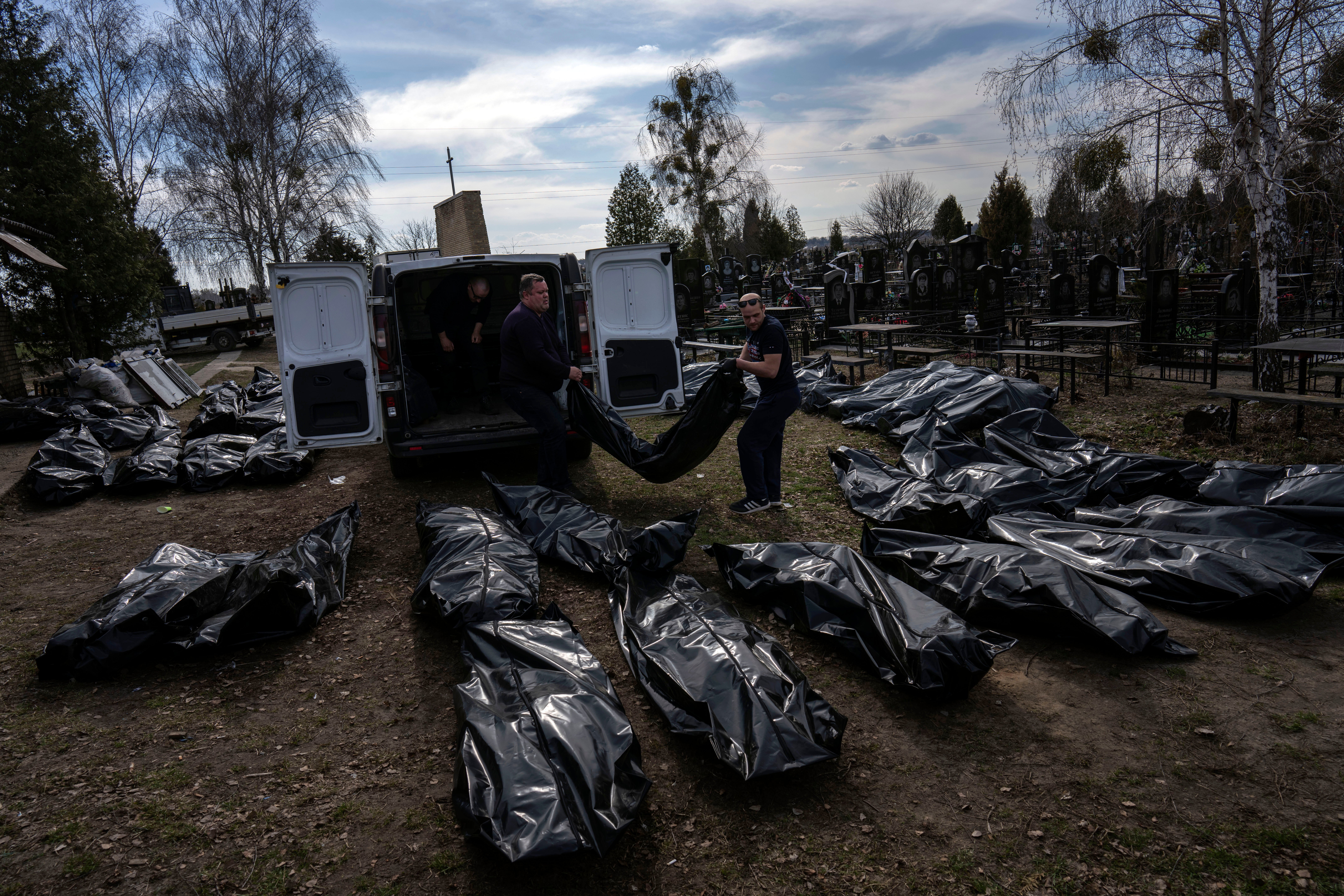 Cemetery workers unload bodies of killed civilians from a van in the cemetery in Bucha