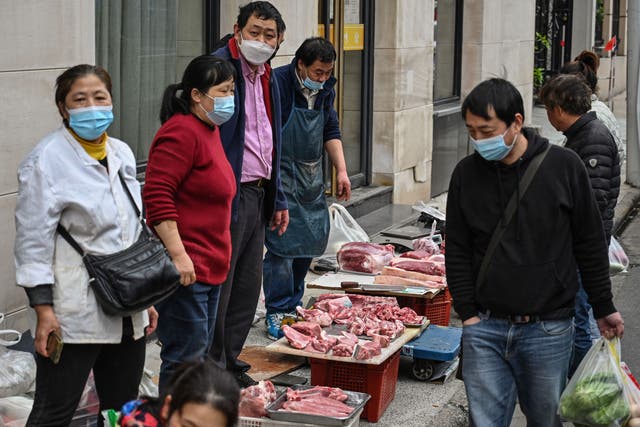 <p>Vendors sell meat in front of a local market in Shanghai’s Jing’an district on 31 March</p>