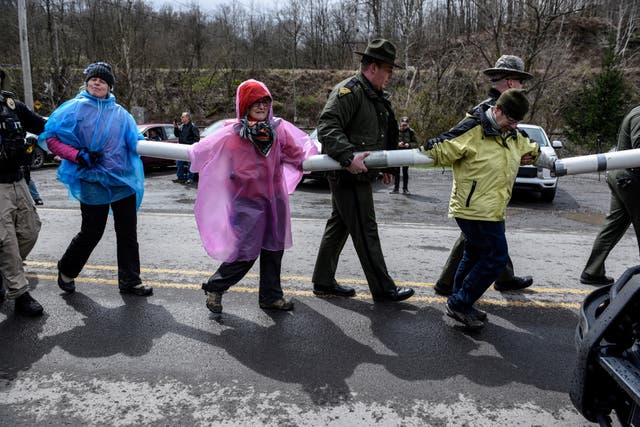 La policía aleja a las personas que están encadenadas durante una protesta contra el senador estadounidense Joe Manchin (D-WV) mientras bloquean la planta de energía de residuos de carbón de Grant Town en Grant Town, Virginia Occidental, EE. UU., 9 de abril de 2022