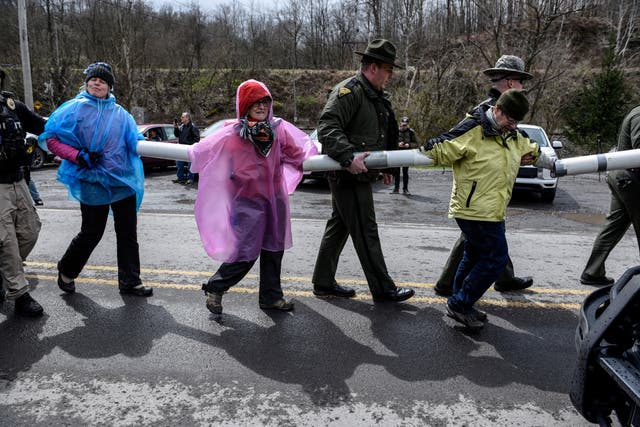 <p>Police lead people away who are chained together during a protest against U.S. Senator Joe Manchin (D-WV) as they blockade the Grant Town Coal Waste Power Plant in Grant Town, West Virginia, U.S., April 9, 2022</p>