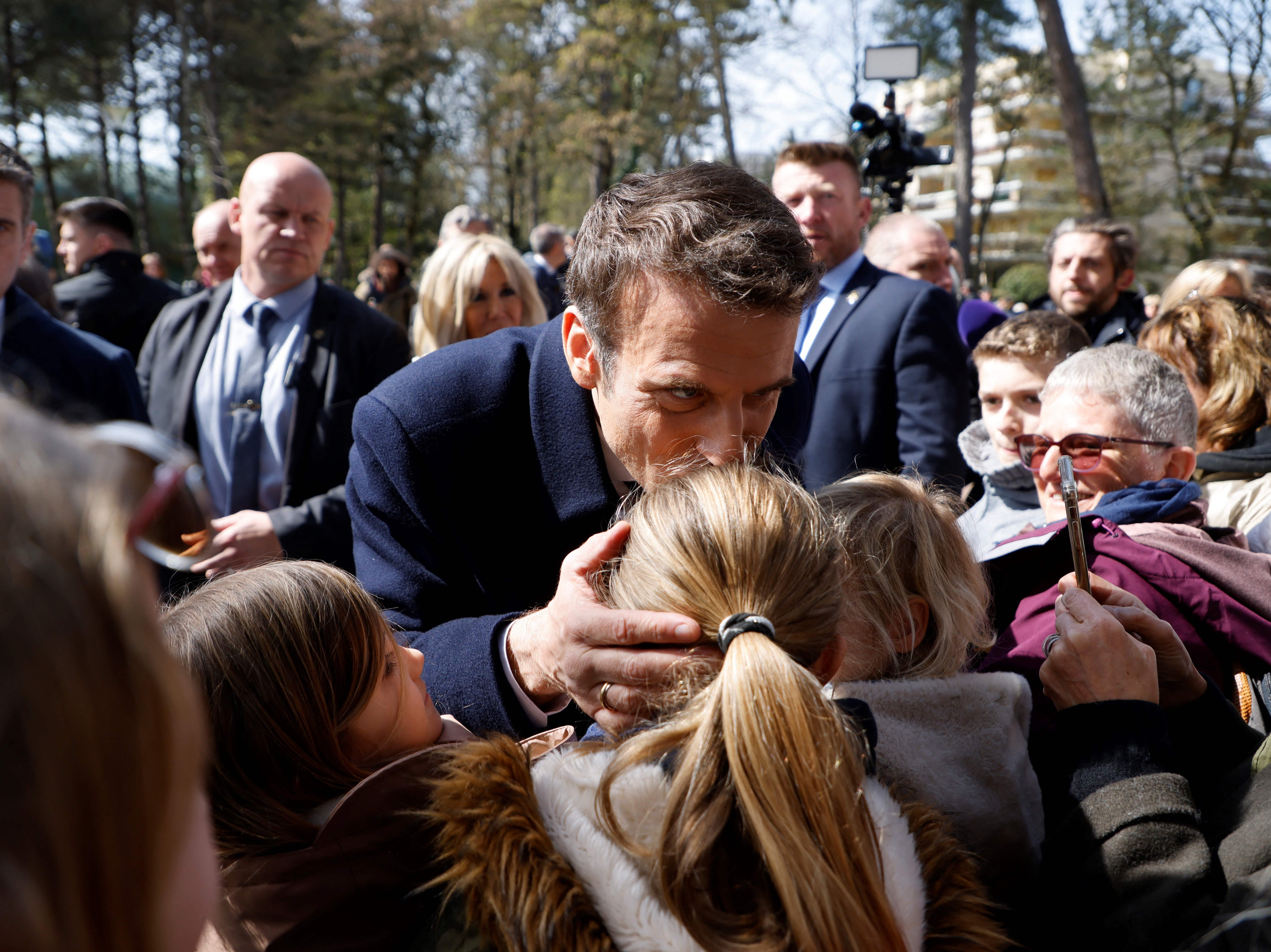 Emmanuel Macron kisses a young child on the head as he speaks with onlookers after casting his ballot in Le Touquet