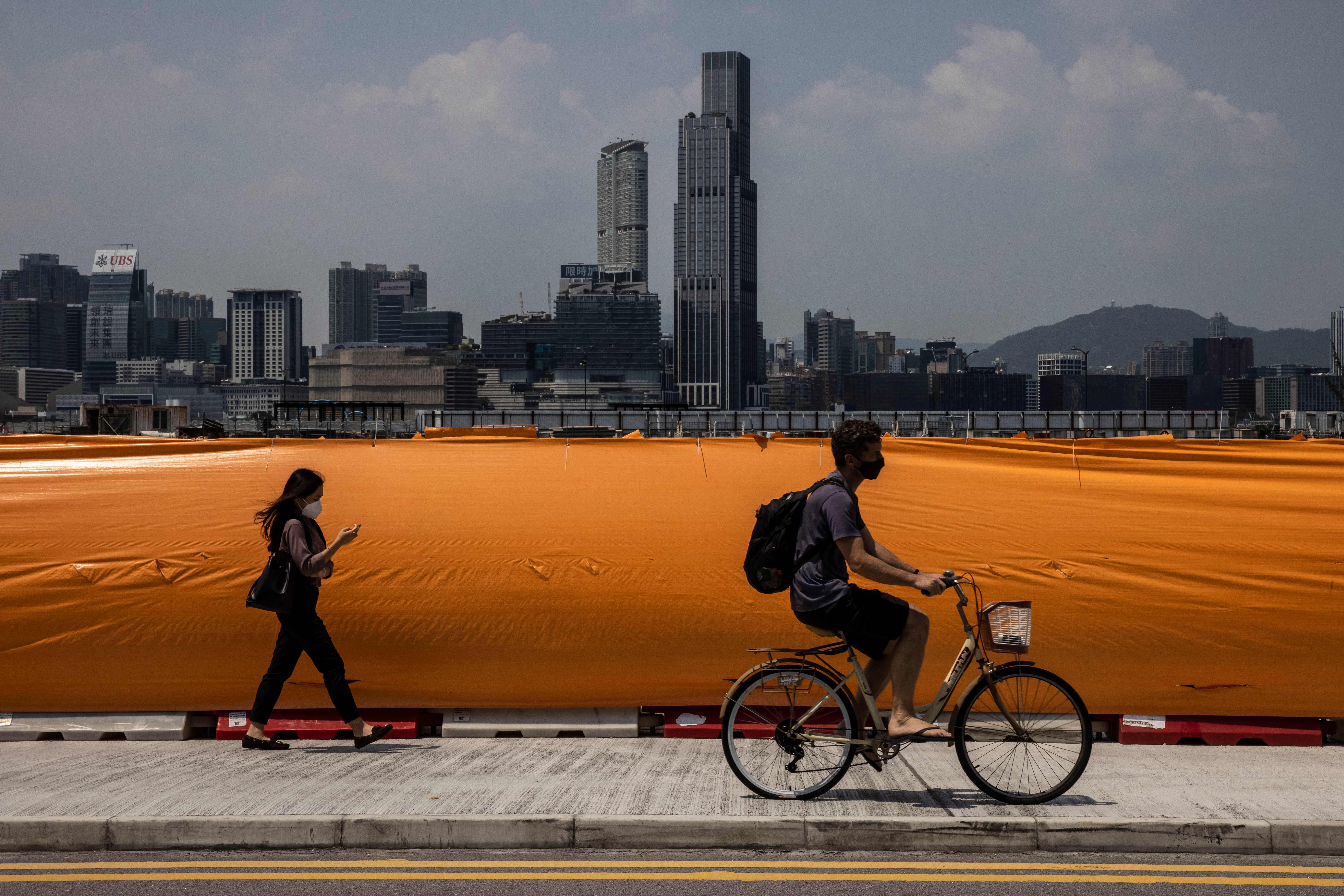 A man rides a bicycle next to Victoria Harbour