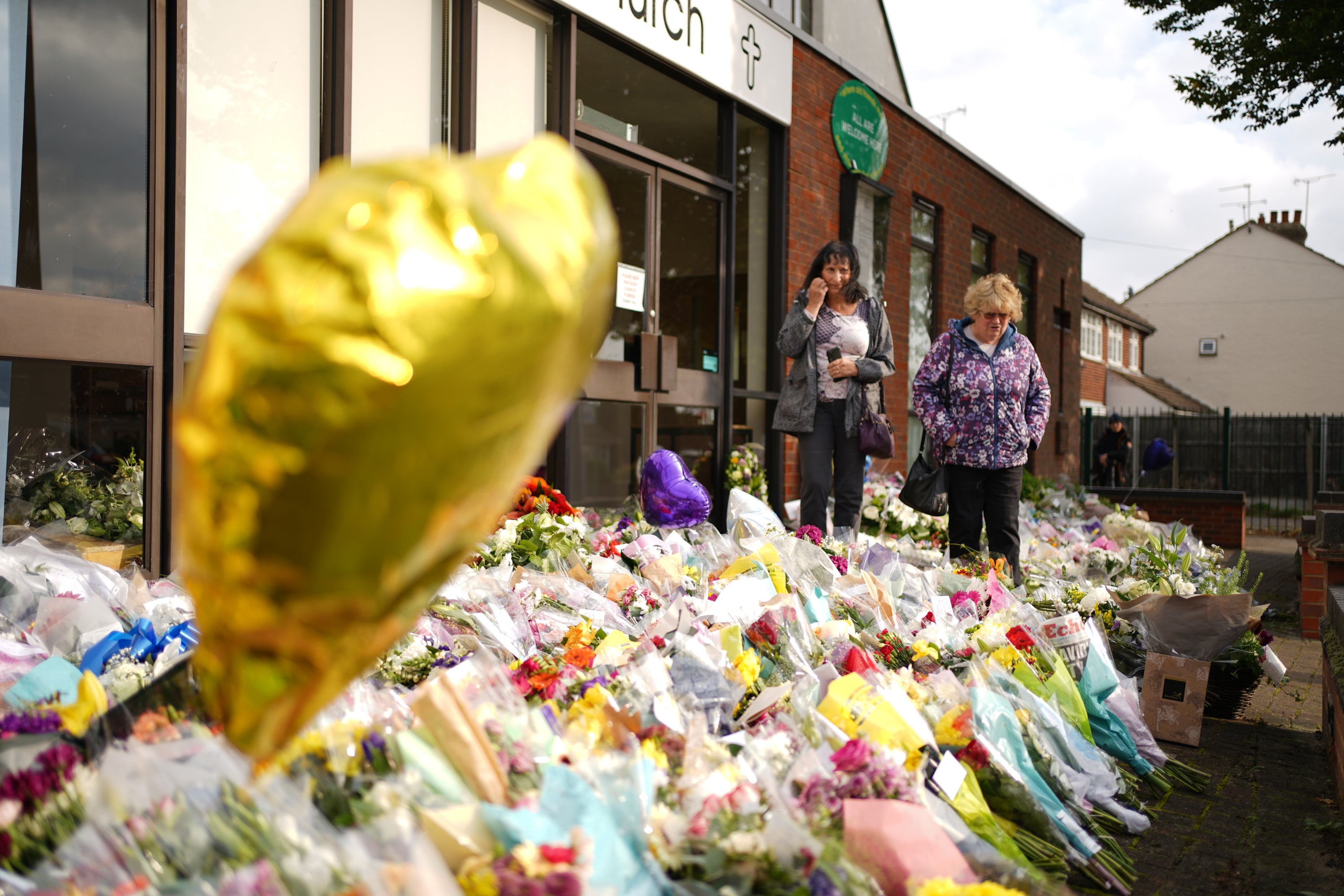 People look at the floral tributes left outside the Belfairs Methodist Church in Leigh-on-Sea
