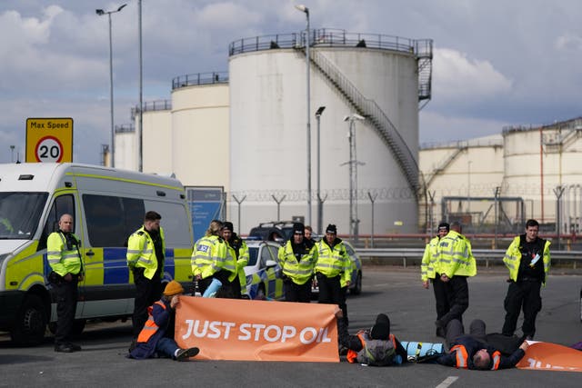 Police officers look at activists from Just Stop Oil taking part in a blockade at the Kingsbury Oil Terminal, Warwickshire (PA)