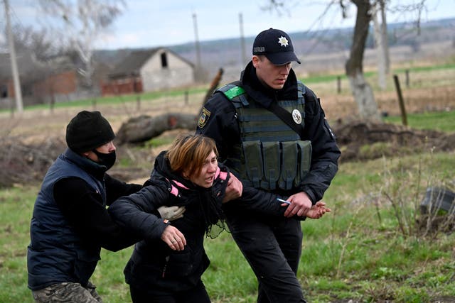 La esposa de un civil reacciona después de que su cuerpo fuera exhumado de una tumba poco profunda cerca de su casa en el pueblo de Andriivka, región de Kiev.