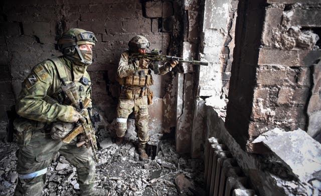 <p>Russian soldiers on patrol at the Mariupol drama theatre, which was hit by an airstrike in March </p>