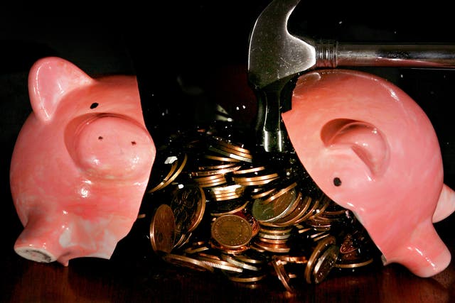 A traditional piggy bank is smashed open with a hammer.