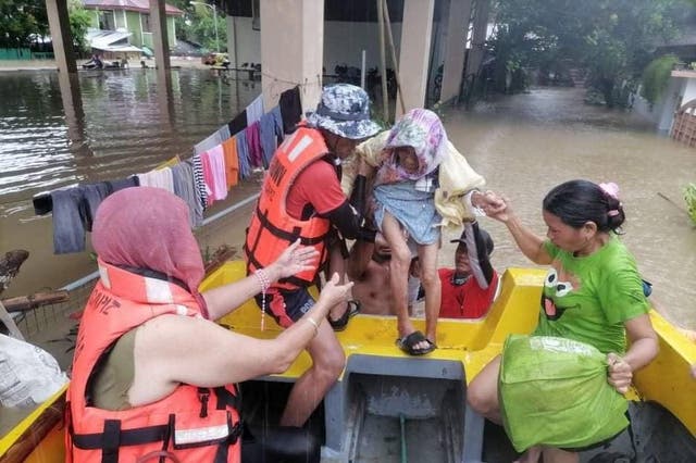 <p>Rescuers assisting an elderly person into a raft in a flooded village in Sigma, Philippines</p>