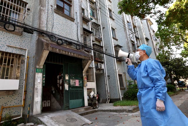 <p>A volunteer uses a megaphone to talk to residents at an apartment building in Shanghai </p>