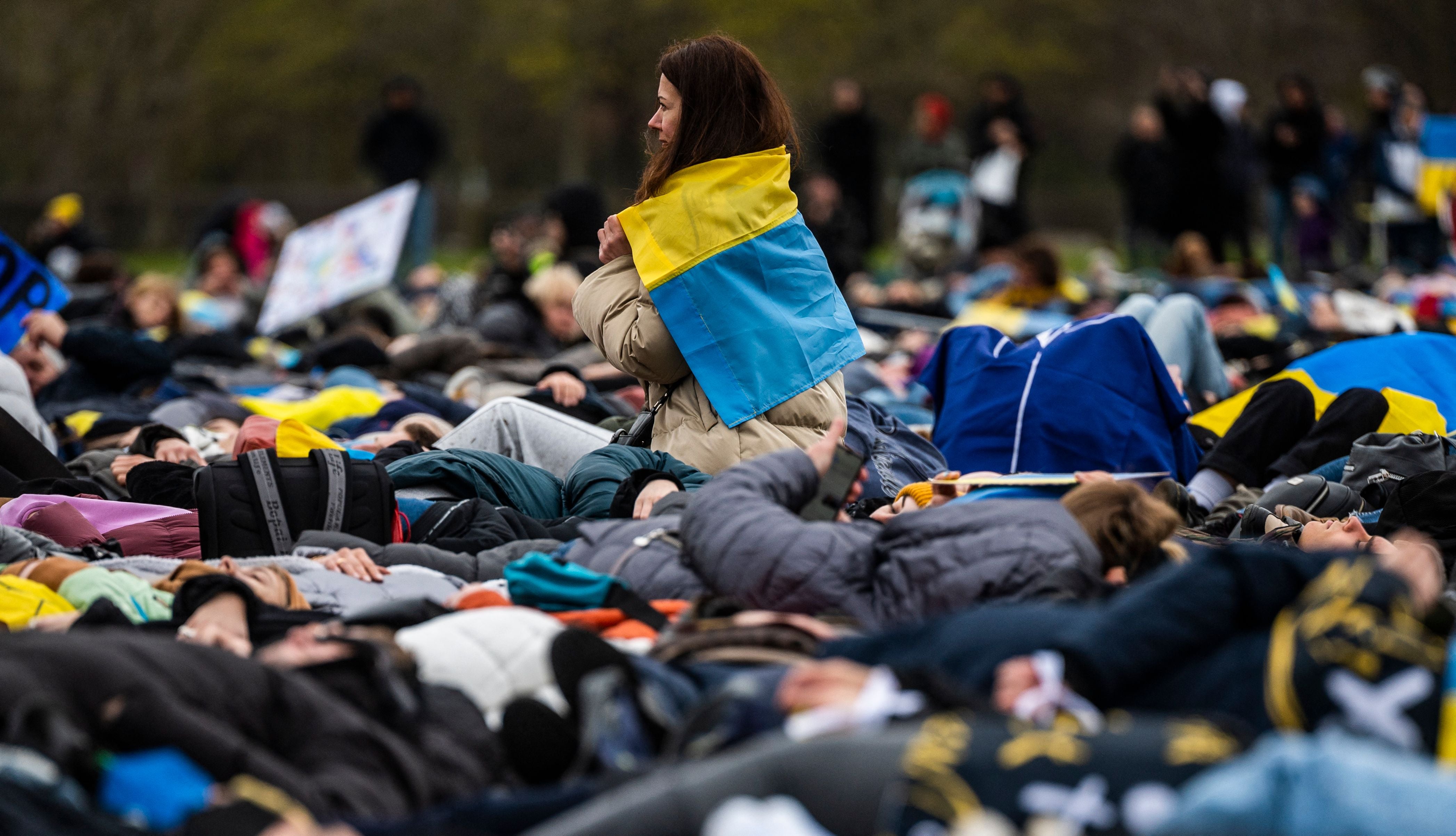 A woman drapped in the Ukraine flag sits among pro-Ukrainian activists staging a ‘die-in’ during a protest in Berlin under the slogan ‘Stop promising, start acting!’