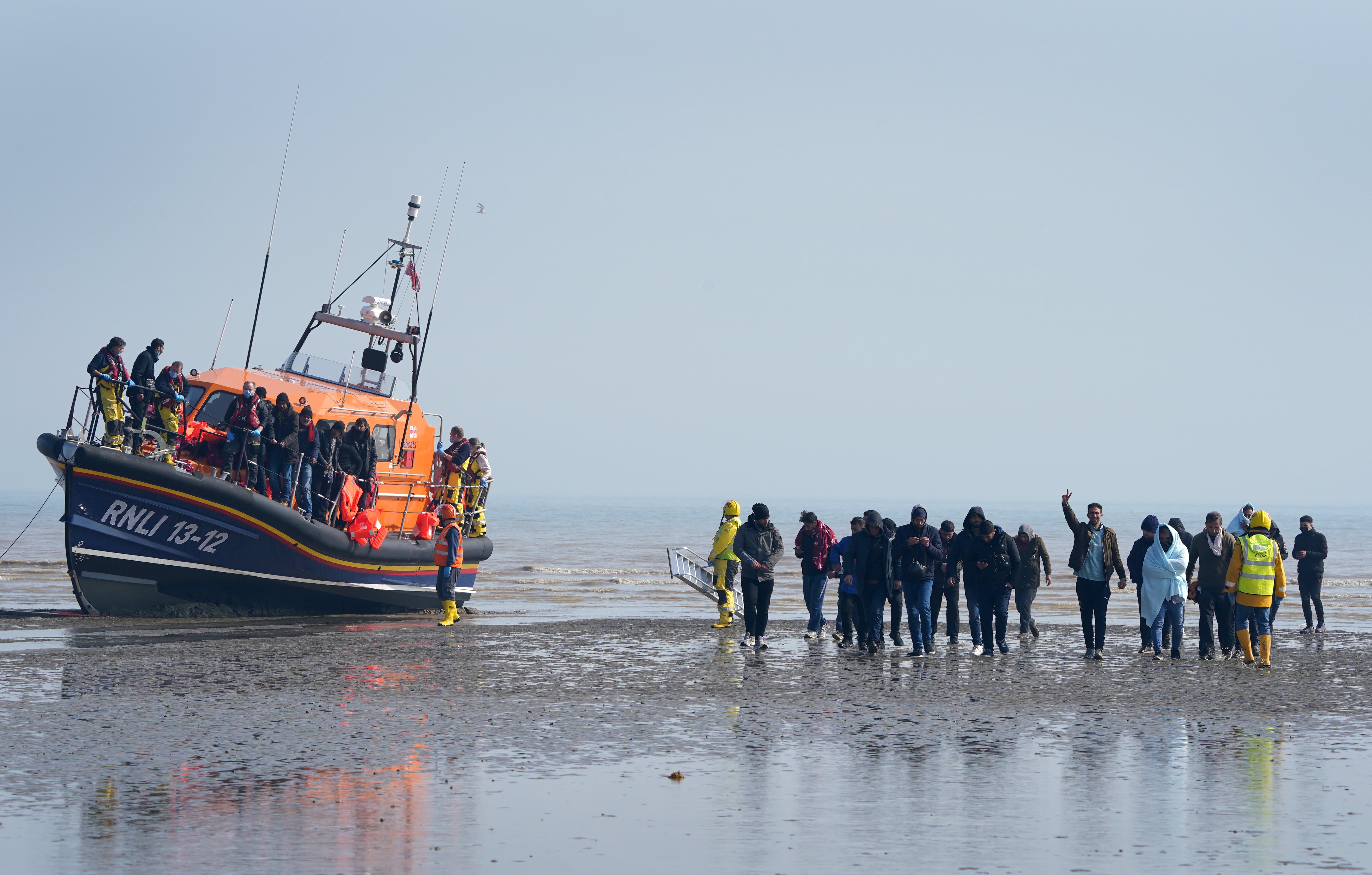A group of people are guided up the beach after being brought into Dungeness, Kent, onboard the RNLI Lifeboat following a small boat incident in the Channel (Gareth Fuller/PA)