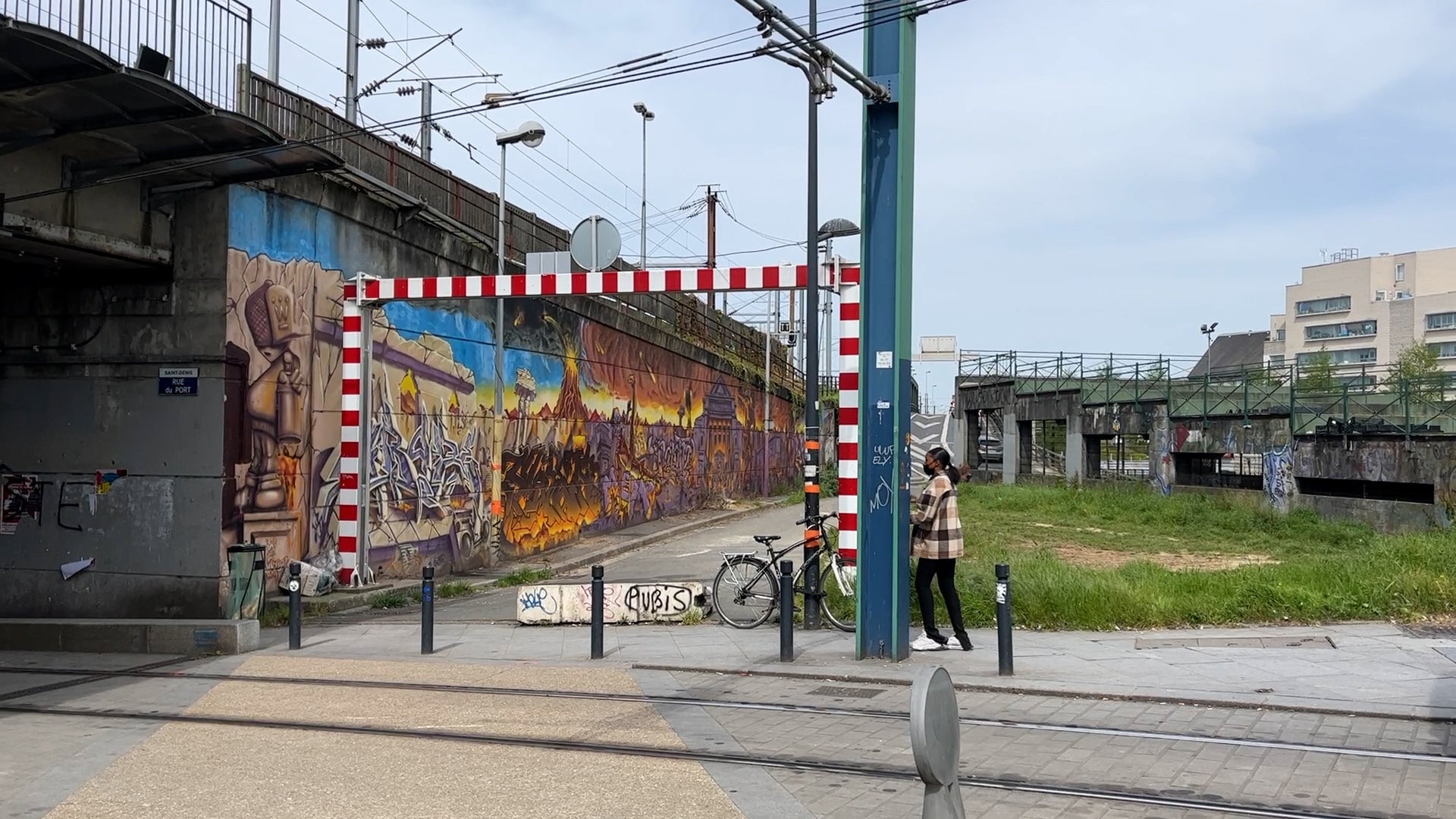 A woman walks past a train track in Seine-Saint-Denis