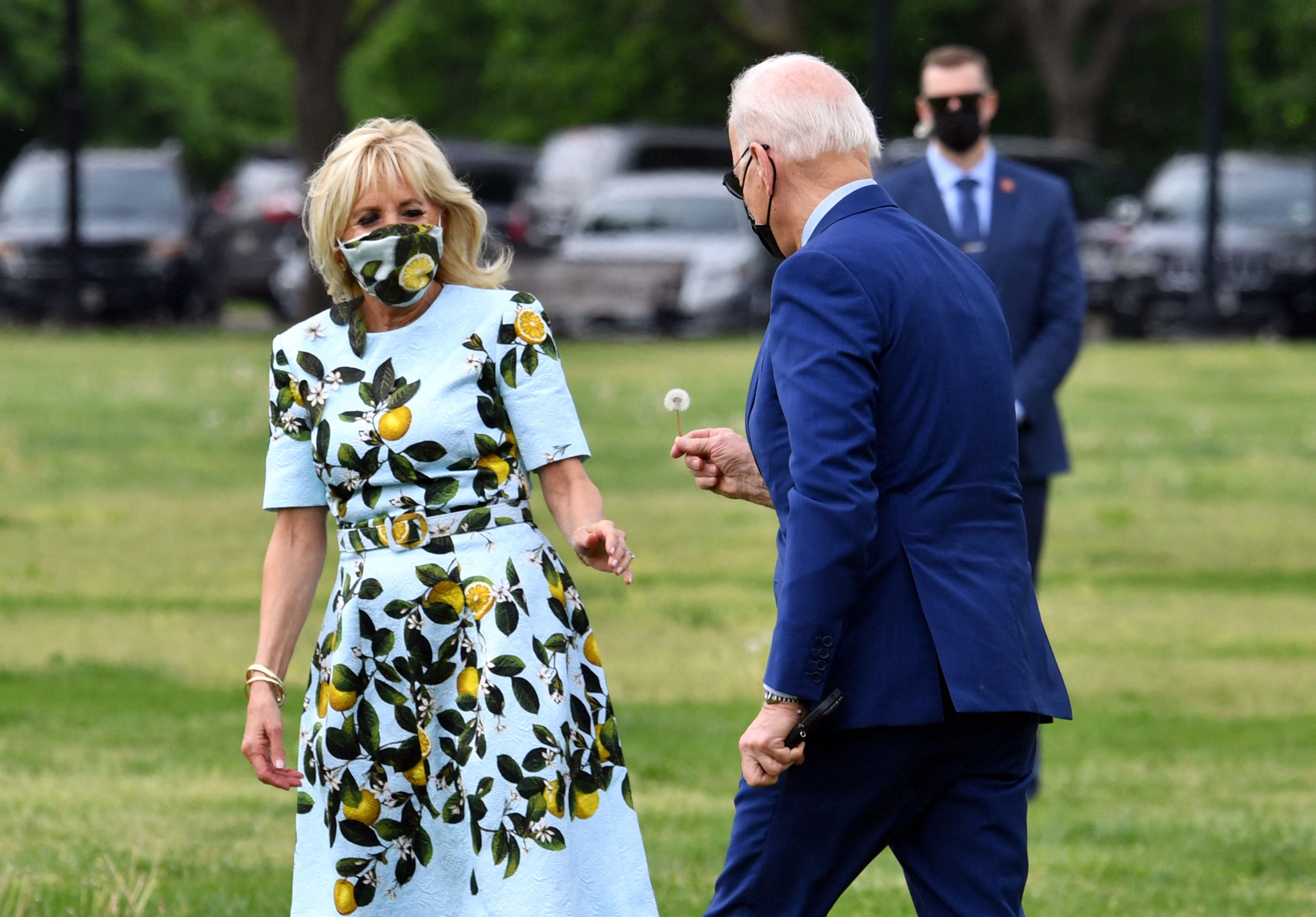 US President Joe Biden gives a dandelion flower to First Lady Jill Biden as they arrive to depart on Marine One from the Ellipse in Washington, DC, on 29 April 2021