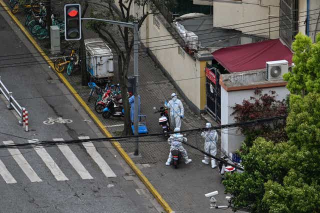 <p>Police officers wearing PPE stand next to the entrance of a neighbourhood during a Covid lockdown in the Jing’an district in Shanghai</p>