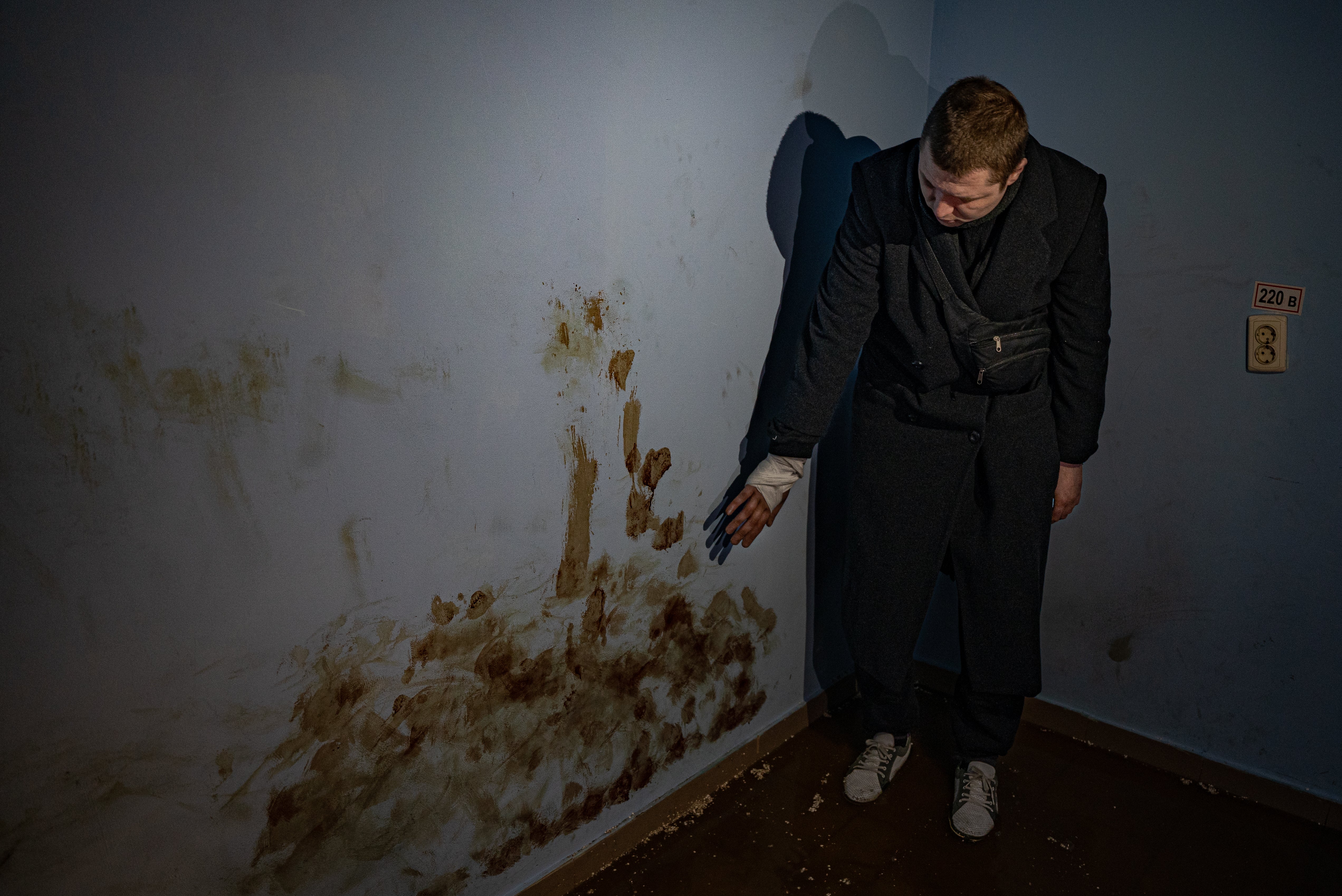 Andrei, one of eight civilians held in an underground torture chamber in Trostyanets, shows his blood on the wall of the cell