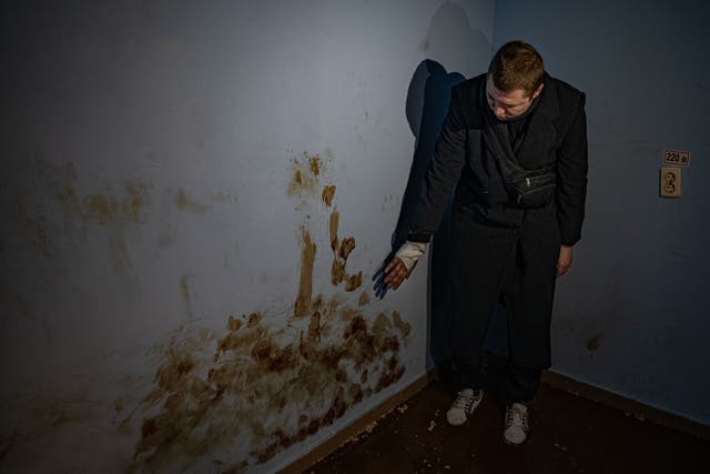 <p>Andrei, one of eight civilians held in an underground torture chamber in Trostyanets, shows  his blood on the wall of the cell</p>
