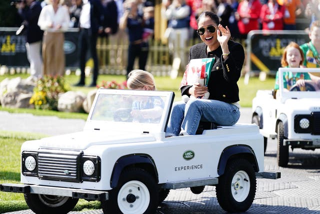 The Duchess of Sussex is driven by a child in a toy Land Rover at the Jaguar Land Rover Driving Challenge during the Invictus Games (PA)