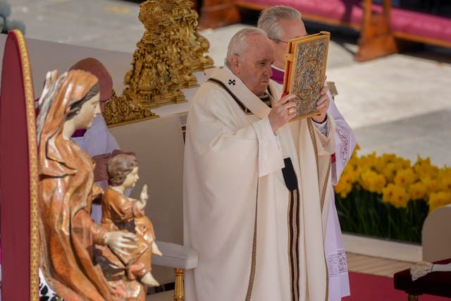 <p>Pope Francis hoists the Gospel book during the Catholic Easter Sunday mass at the Vatican yesterday </p>