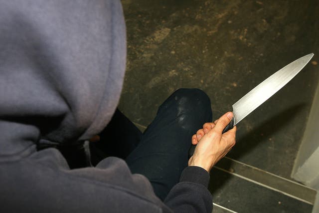 File photo of a man in a hoodie holding a knife. (Katie Collins/PA)