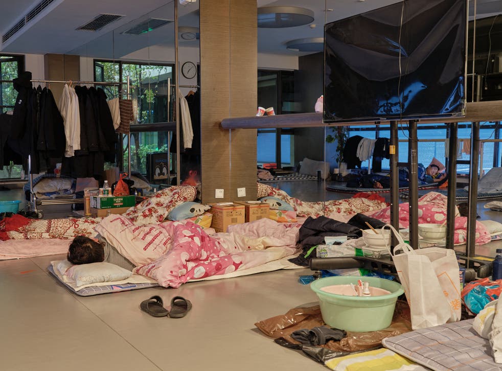<p>A community worker takes a nap at a temporary bed at a gym in a compound during a Covid-19 lockdown in Pudong district in Shanghai</p>